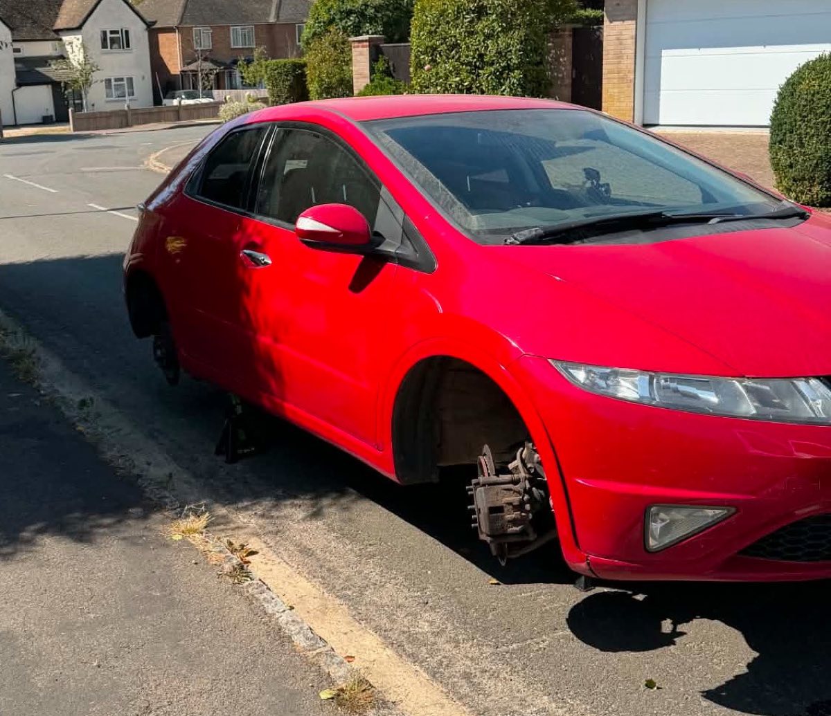 Brake job in progress on a red Honda Civic, on the customer's street